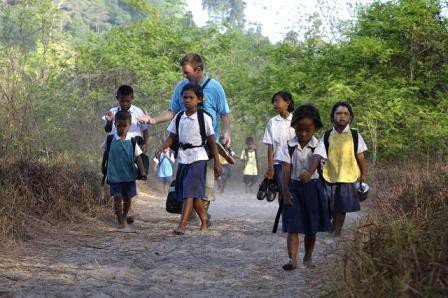 Philip walking the forest path with Moken children in school uniform on their way to school