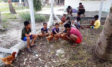 Moken children sitting with the newly arrived chickens outside the church