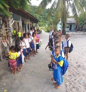 Moken children in school uniform lined up on the village path on a school morning