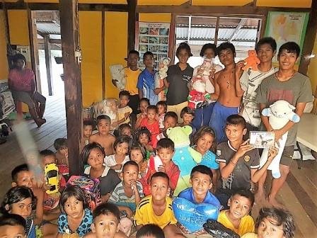 A packed evening gathering of Moken children and families in the wooden house
