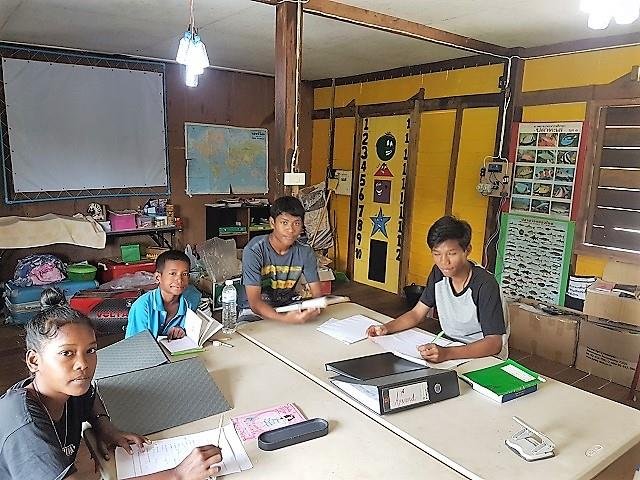 Older Moken students working through their books at the learning-centre tables