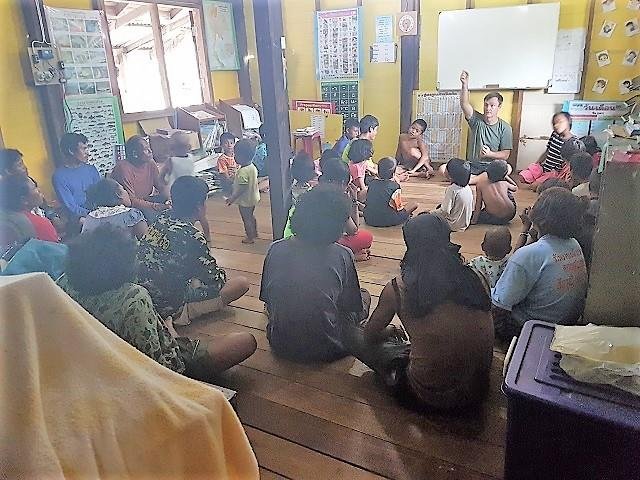 A full class of Moken children seated in a circle for a lesson at the learning centre