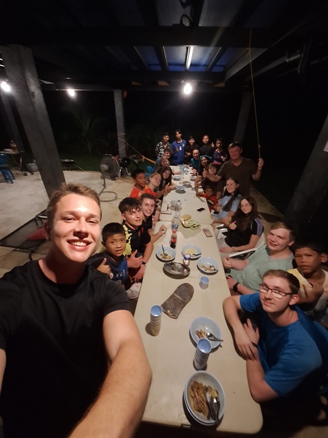 The Global Challenge team of fourteen and Moken children sharing an evening meal around a long table