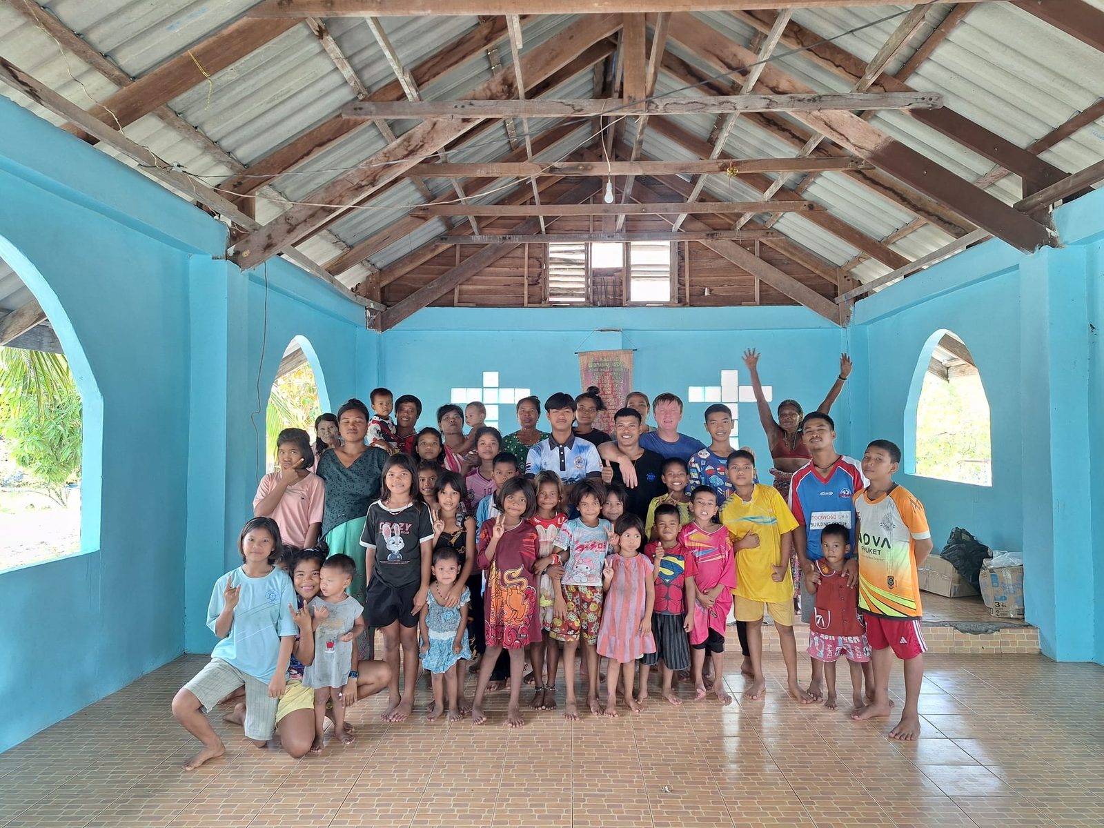 Group photo of about fifty Moken children, young people and adults with a foreign man, inside the turquoise church on 16 August