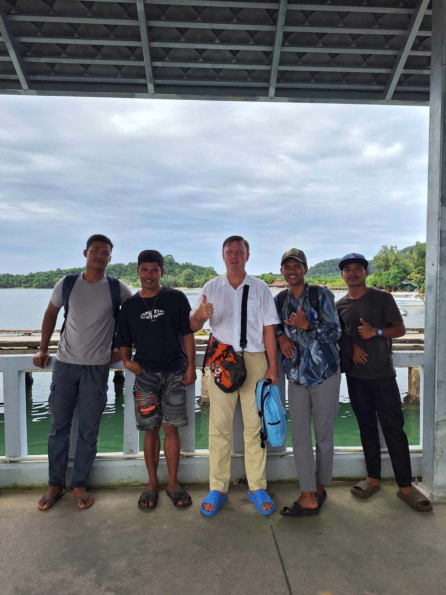 On the way to the meeting of the churches of Ranong: five men, a Western man in the centre with four local young men, under a pier shelter with the sea and green islands behind